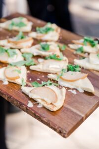 Pear & Arugula Flatbread cut into slices for easy tray passed catering on a wooden serving platter