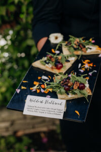 Waldorf Flatbread with garlic oil and topped with red grapes, creamy gorgonzola, candied walnuts, baby arugula, and reduced balsamic