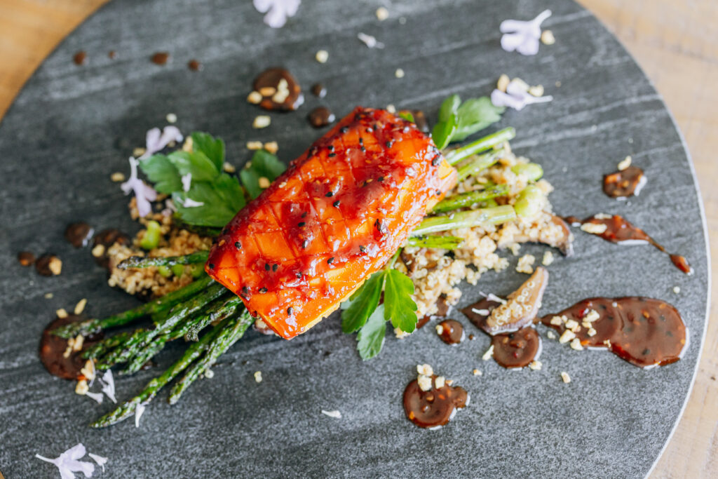 Vegetarian entree on a black plate with quinoa sauce and asparagus available for events in Southern California via full service catering