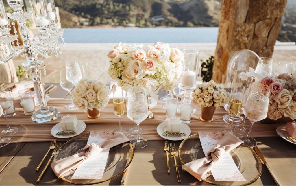 Wedding Reception Table Setting with Clear Gold Lined Plates and Pink and White Florals with Champagne Flutes