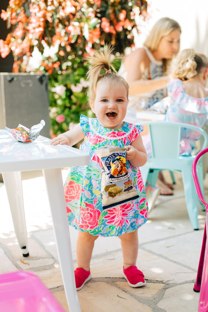 Young child standing next to table holding a bag of easy to eat snack