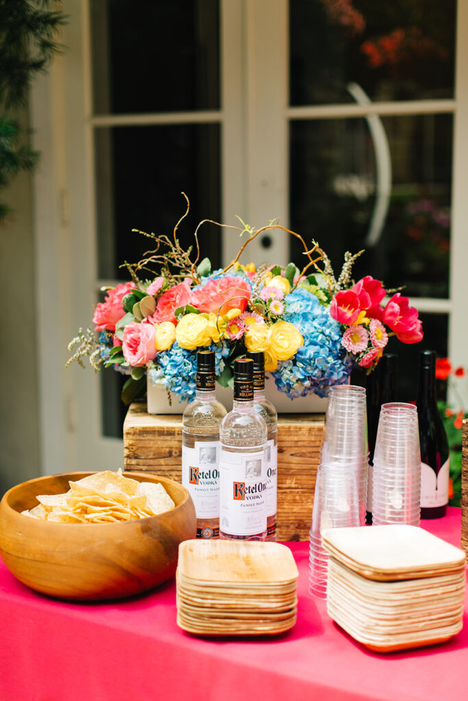 Kettle One Vodka bottles next to cups and florals and plates 