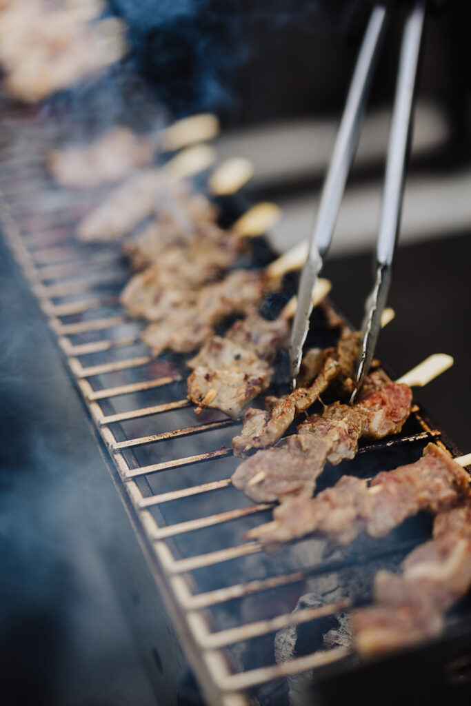 Grilled Yuzu Jalapeño Beef Short Rib Skewers on a Yakitori Live Action Grill at an outdoor event