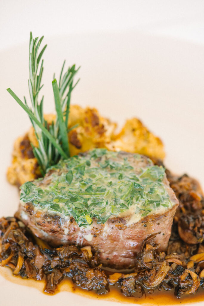 Herb Butter Filet Mignon with Roasted Wild Mushroom Shallot Whiskey Sauce with fresh rosemary springs on a white plate 