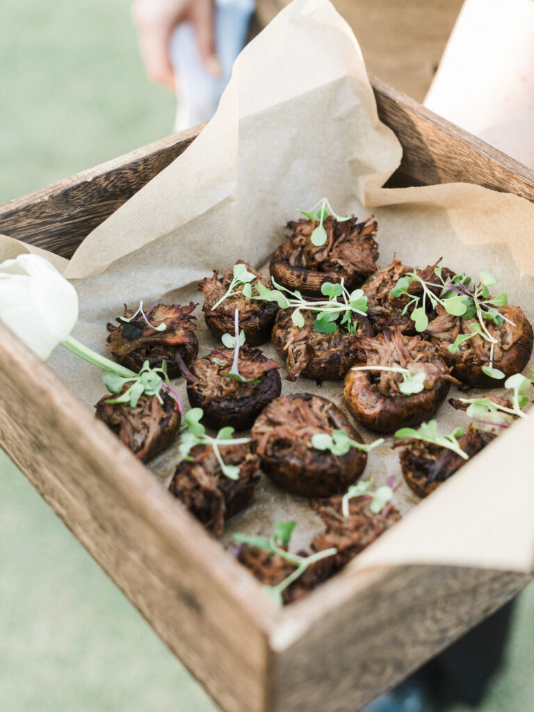 Bourbon Glazed Marinated Short Ribs Stuffed Cremini Mushrooms in a box with brown butcher paper as a passed appetizer at an event