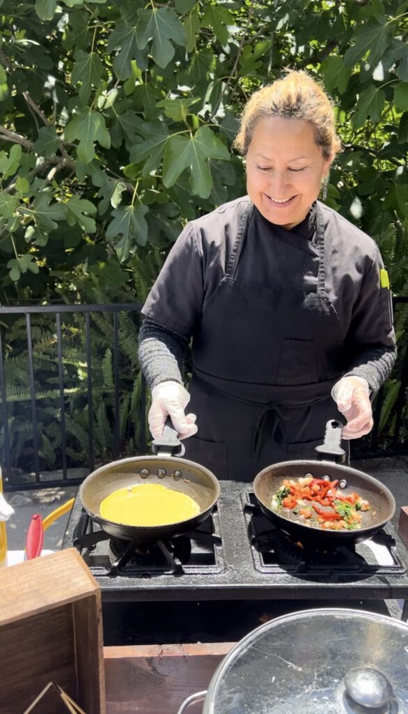 Brunch Omelet station at La Venta Inn with a chef preparing eggs in one pan and sauteed vegetables in the other pan in front of a lush green backdrop 