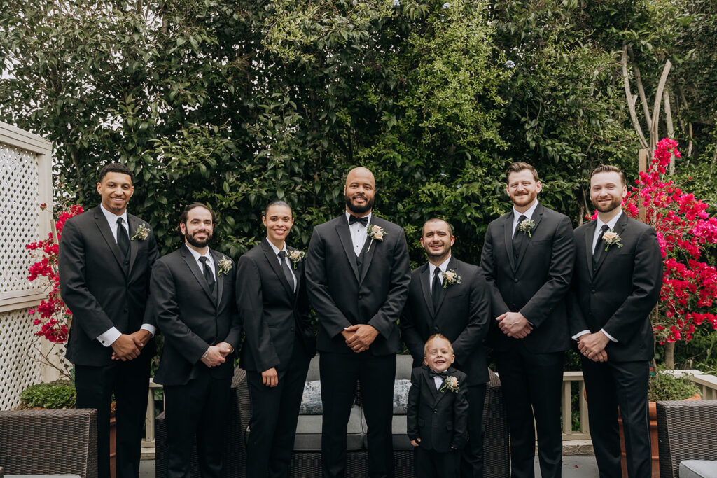 Wedding Party Posing With Groom at the Hideaway Suite After Getting Ready Before The Wedding Ceremony Dressed in Black Suits