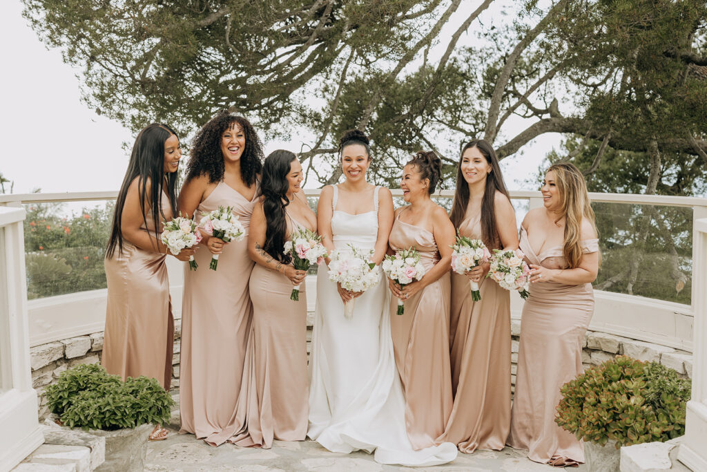 Bridesmaids posing with the bride after getting ready and before the wedding ceremony begins in front of a tree at La Venta Inn