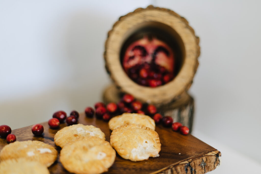 Brie & White Chocolate Pillows from the Made by Meg Catering Holiday Menu in front of cranberries and a half of a pomegranate  