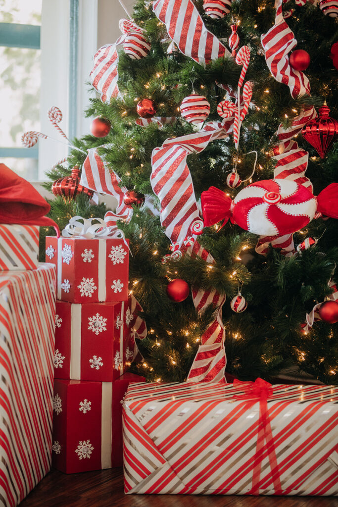 Candy Cane Holiday Decor on the Christmas Tree at La Venta Inn in Palos Verdes during the A Very La Venta Holiday lunch event. The Christmas tree is surrounded by wrapped presents in red, white, and silver wrapping paper tied with a bow. The Christmas tree is decorated with red and white striped ribbon, large red and white swirl mint candies, warm glowing lights, and red and white ornaments.
