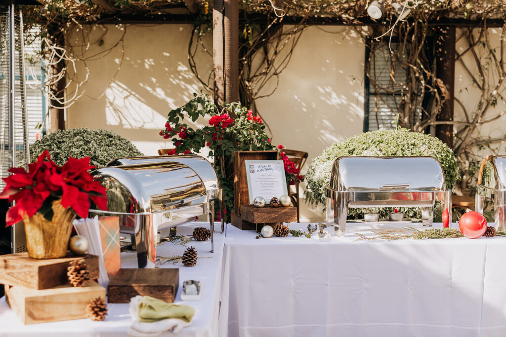 Courtyard buffet station with multiple silver chafing serving dishes with warmers on a table with white tablecloths at La Venta Inn in Palos Verdes