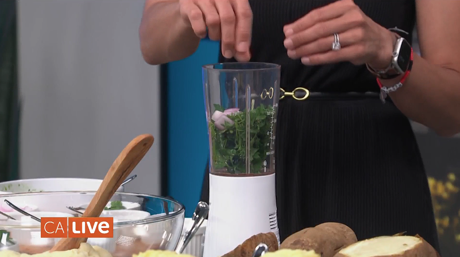 Close up angle of the blender with ingredients to make a chimichurri. The ingredient inside the blender consists of fresh parsley and onions.