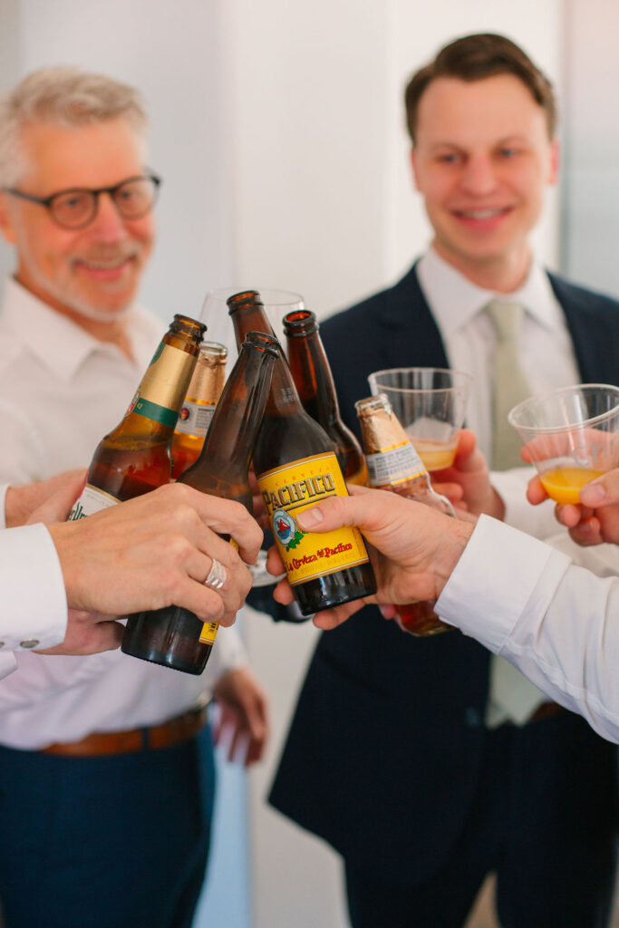 A group of guys toasting their beers and drinks to celebrate. 